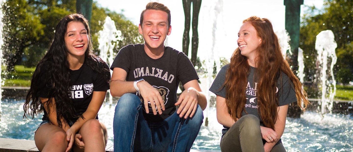 三个韦德体育app官网的学生坐在喷泉边，笑个不停.