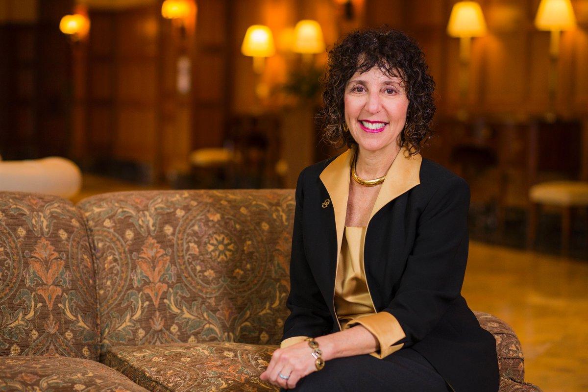 President Ora Hirsch Pecovitz Sitting on a couch smiling at the camera